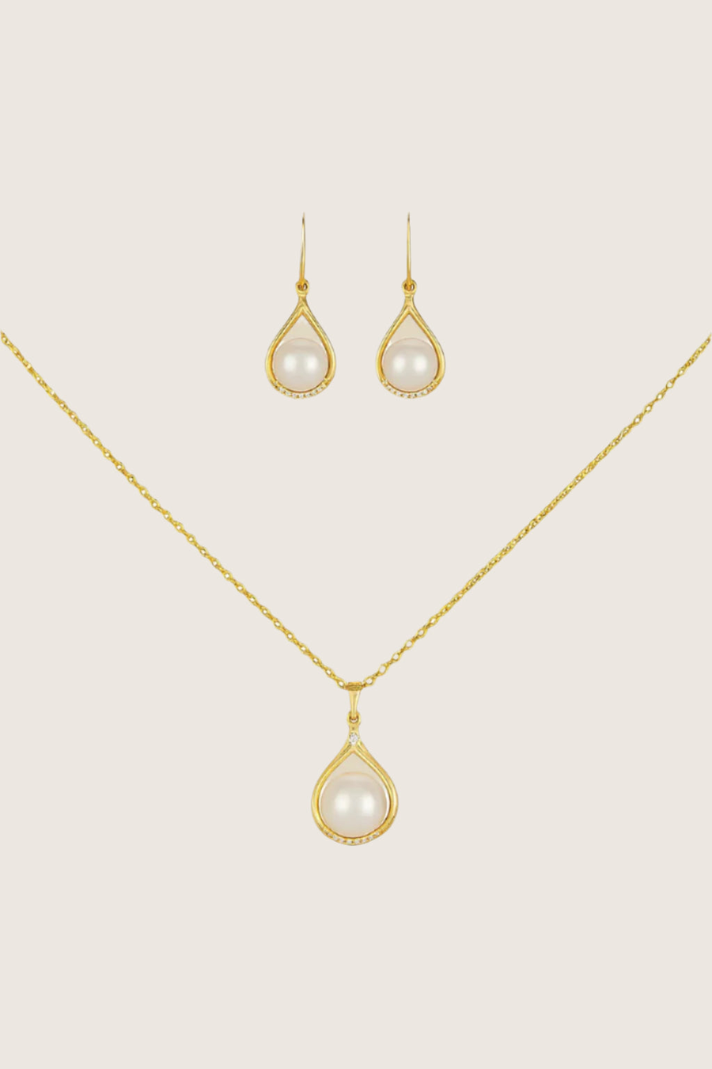 Gold necklace and earrings with pearl drops on a white background